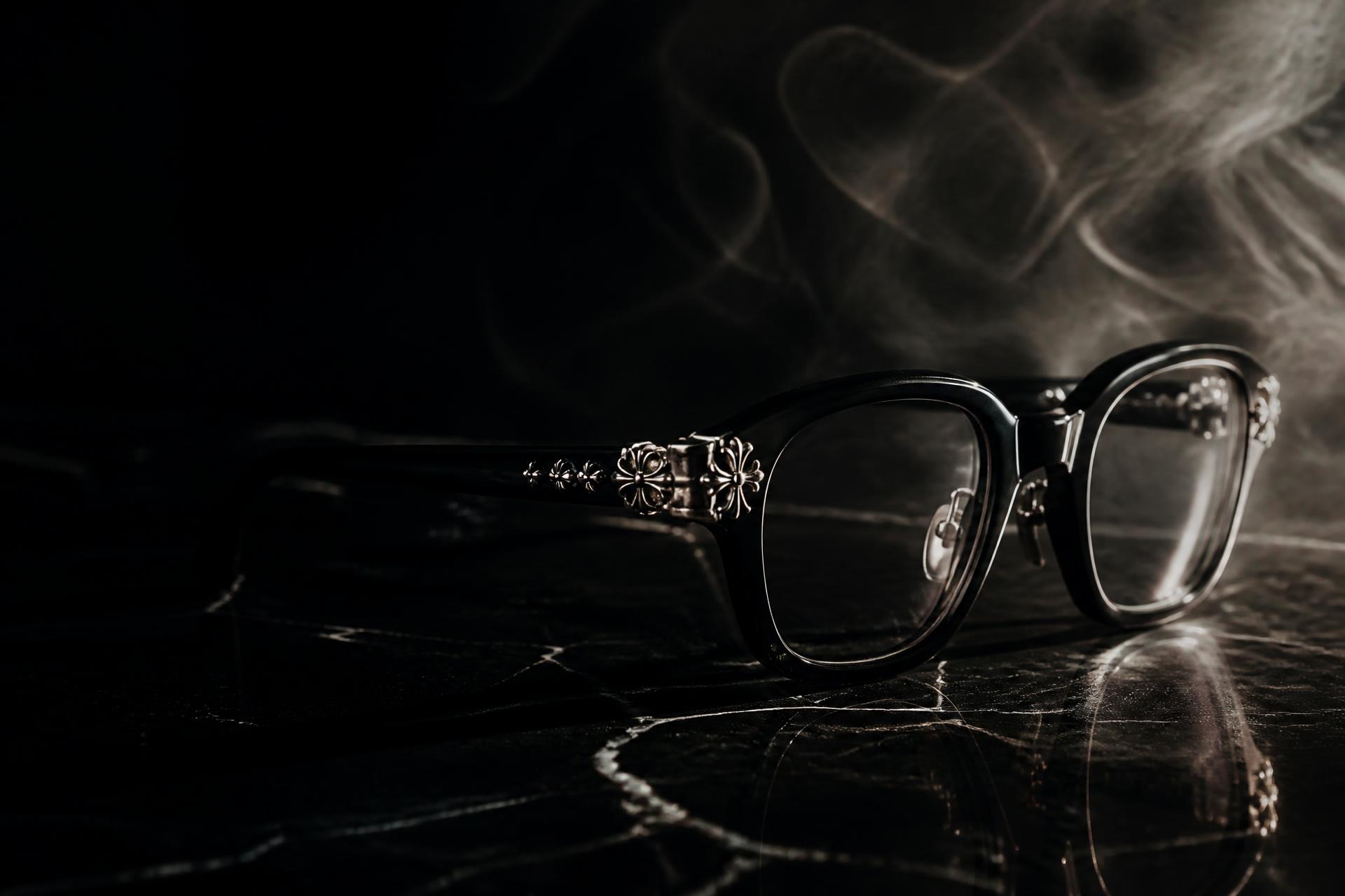 Vyzor black acetate eyewear with heavy silver hardware on black marble beside a lit black candle and silver chain, cinematic gothic still life